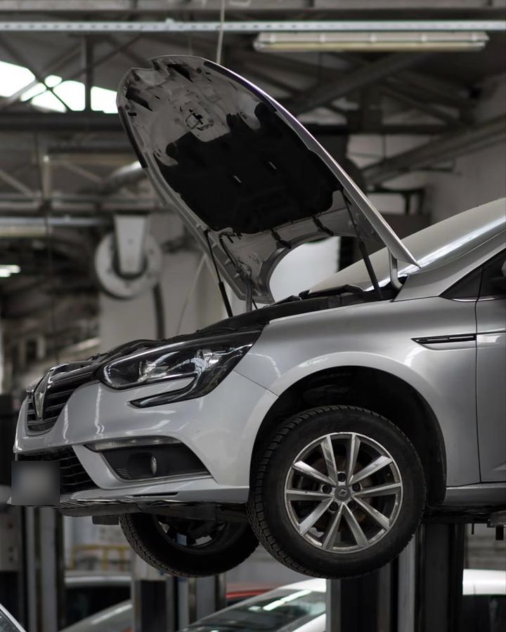 Auto mit geöffneter Motorhaube auf der Hebebühne in der Werkstatt